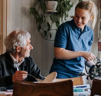 Younger woman watering plants for older man