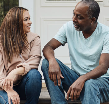 Man and woman talking while sitting on their front steps