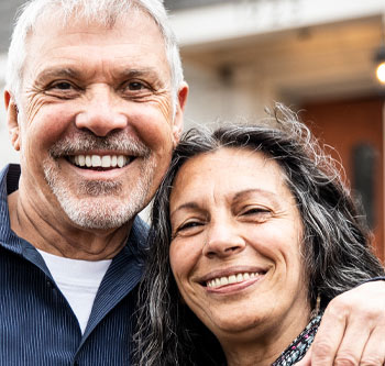 Older couple smiling together in front of their home